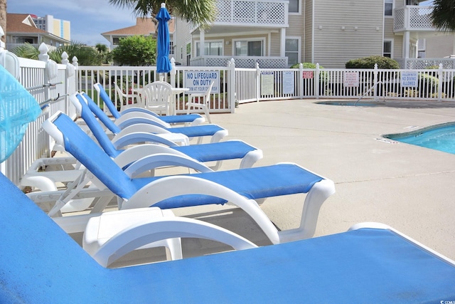 view of swimming pool featuring a patio and fence