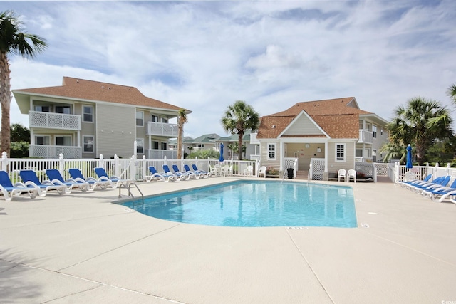 community pool featuring a residential view, a patio, and fence