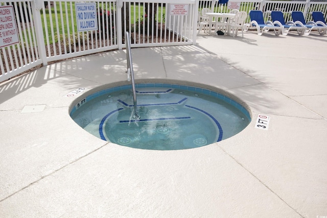 view of pool with a hot tub and fence