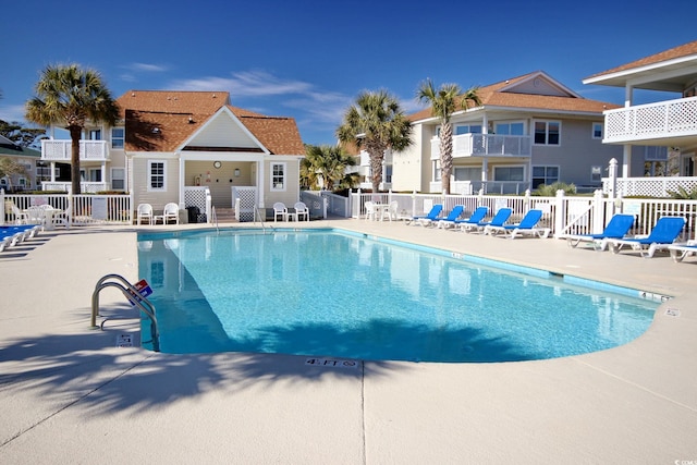 community pool with a patio area and fence