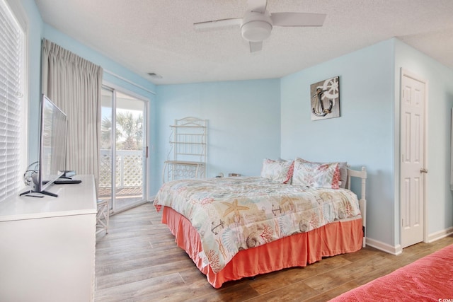 bedroom with wood finished floors, baseboards, visible vents, a textured ceiling, and access to outside