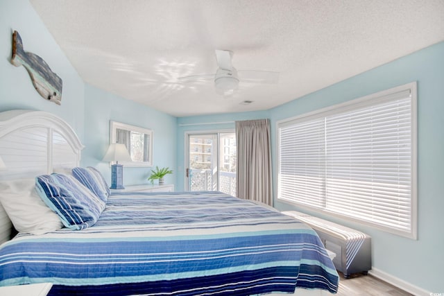 bedroom featuring a textured ceiling, a ceiling fan, baseboards, and wood finished floors