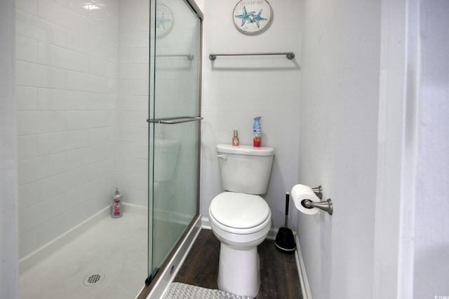 bathroom featuring a shower stall, toilet, baseboards, and wood finished floors