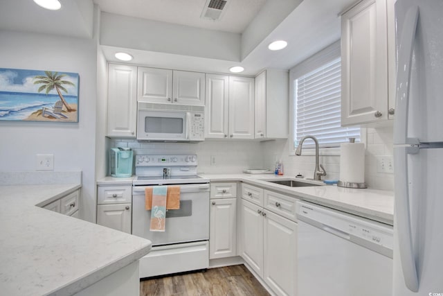 kitchen featuring visible vents, backsplash, white cabinets, white appliances, and a sink