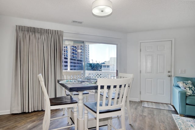 dining area featuring visible vents, a textured ceiling, and wood finished floors