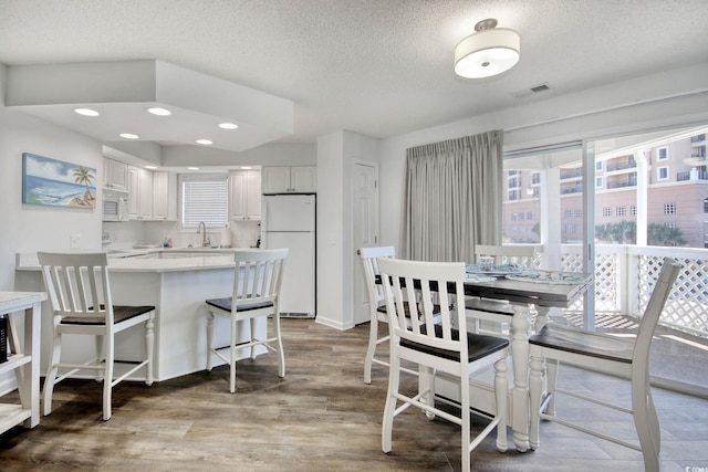 dining room featuring visible vents, a textured ceiling, and wood finished floors