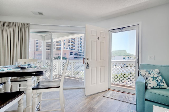 doorway to outside with wood finished floors, visible vents, and a healthy amount of sunlight