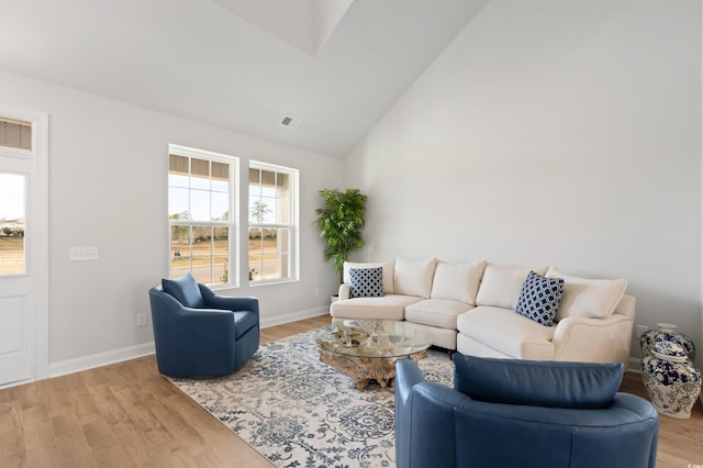 living area featuring visible vents, baseboards, light wood-style floors, and vaulted ceiling