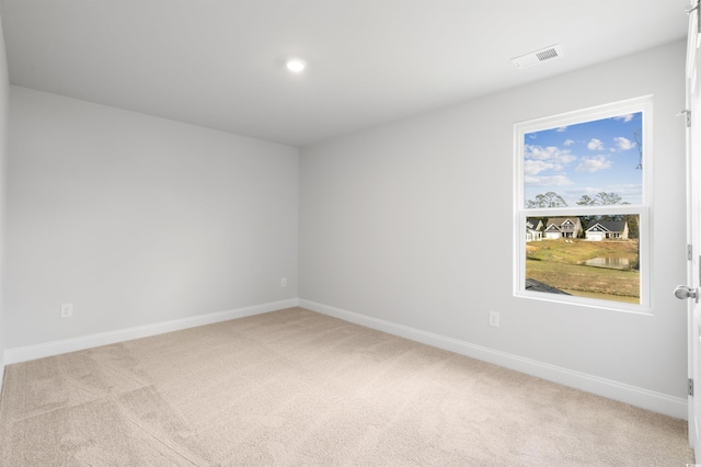 empty room with light carpet, visible vents, and baseboards