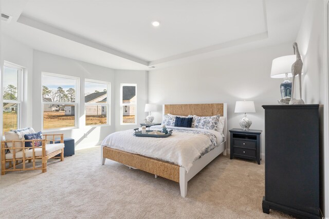 bedroom featuring a raised ceiling, visible vents, and light carpet