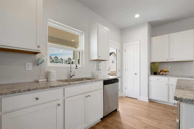 kitchen with light stone counters, white cabinetry, light wood-style flooring, a sink, and dishwasher