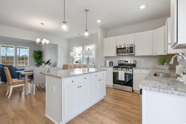 kitchen featuring light wood-type flooring, a kitchen island, appliances with stainless steel finishes, and a sink