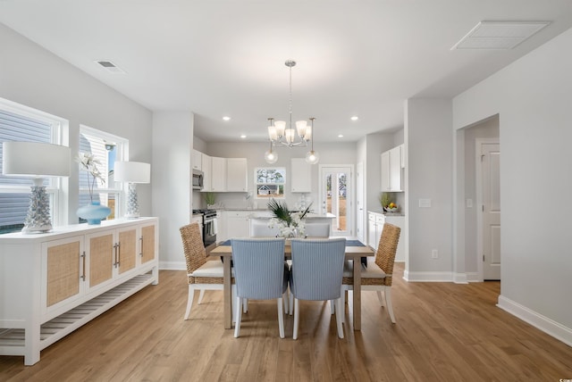dining space featuring an inviting chandelier, light wood-style floors, and visible vents
