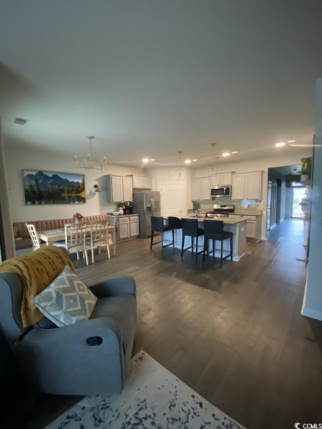 living room with dark wood-type flooring, recessed lighting, a chandelier, and visible vents