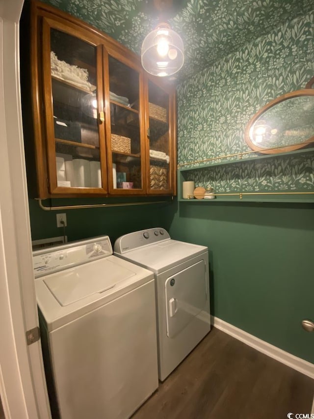 laundry area with dark wood-style flooring, baseboards, cabinet space, washer and clothes dryer, and wallpapered walls