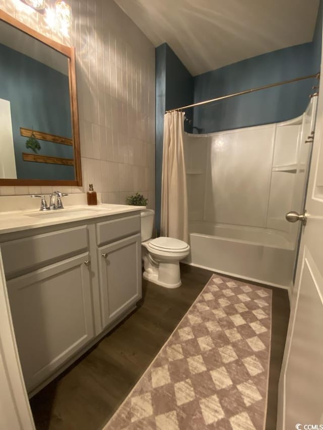 full bath with tile walls, shower / bath combination with curtain, toilet, vanity, and wood finished floors