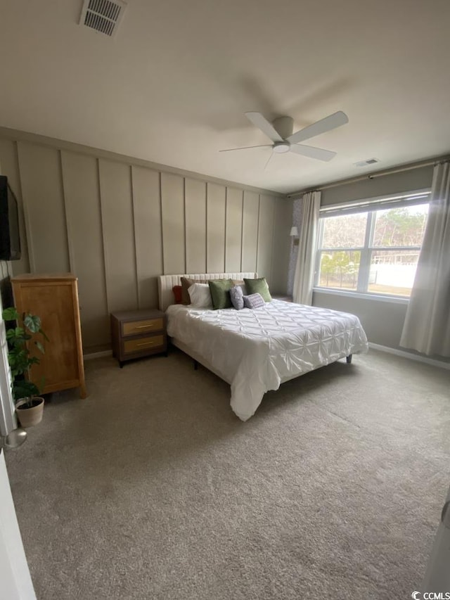 bedroom with visible vents, a decorative wall, light carpet, and ceiling fan