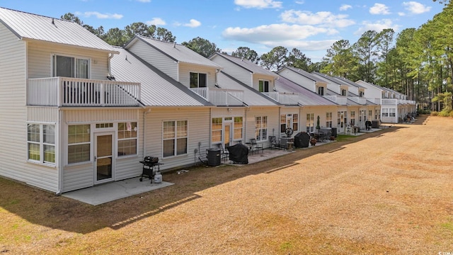 rear view of house featuring metal roof, a patio, and a lawn