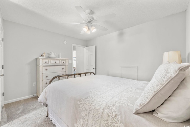 bedroom featuring a ceiling fan, light colored carpet, a textured ceiling, and baseboards