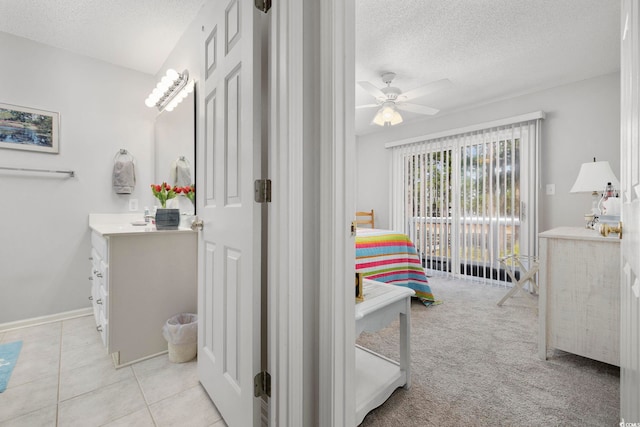 bathroom with a textured ceiling, ceiling fan, tile patterned flooring, vanity, and baseboards