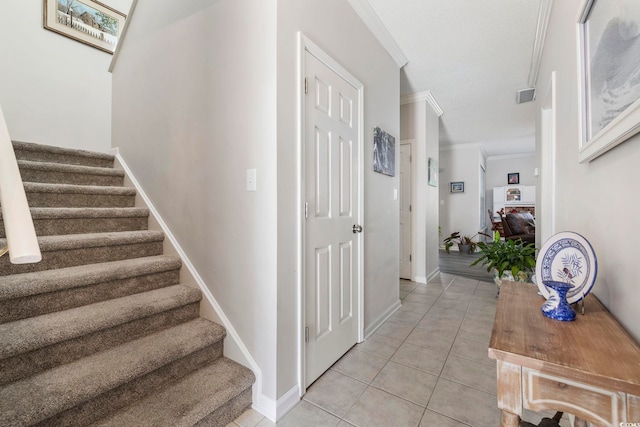 stairway with tile patterned flooring, visible vents, ornamental molding, and baseboards