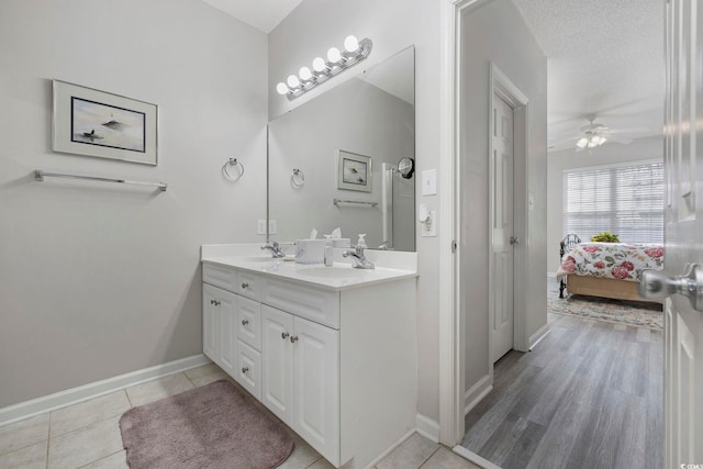 ensuite bathroom featuring double vanity, ensuite bathroom, a sink, a textured ceiling, and tile patterned floors