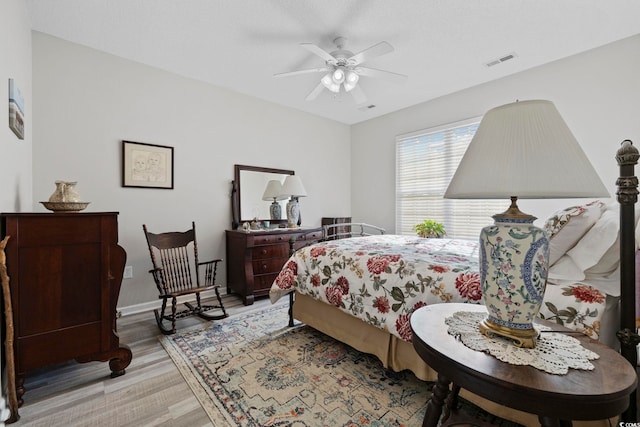 bedroom with a ceiling fan, baseboards, visible vents, and wood finished floors