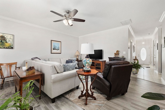 living area featuring a ceiling fan, ornamental molding, a textured ceiling, and light wood finished floors