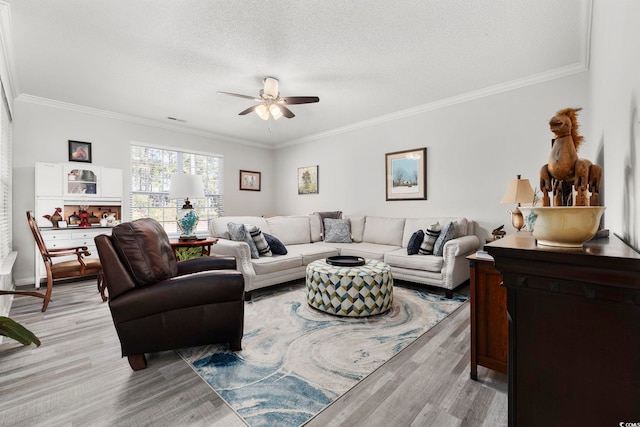 living area with light wood finished floors, a ceiling fan, ornamental molding, and a textured ceiling