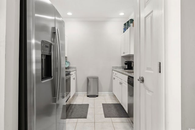 kitchen with light stone counters, light tile patterned floors, stainless steel appliances, ornamental molding, and white cabinets