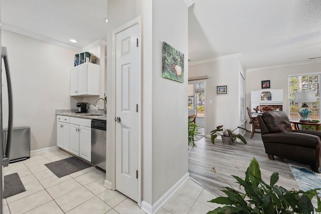 kitchen with light tile patterned floors, a sink, white cabinetry, ornamental molding, and dishwasher