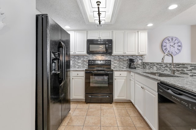 kitchen featuring light stone countertops, black appliances, white cabinetry, and a sink