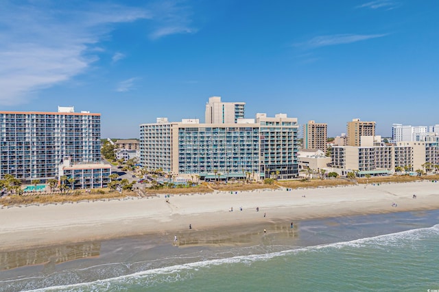 drone / aerial view featuring a water view, a view of city, and a beach view