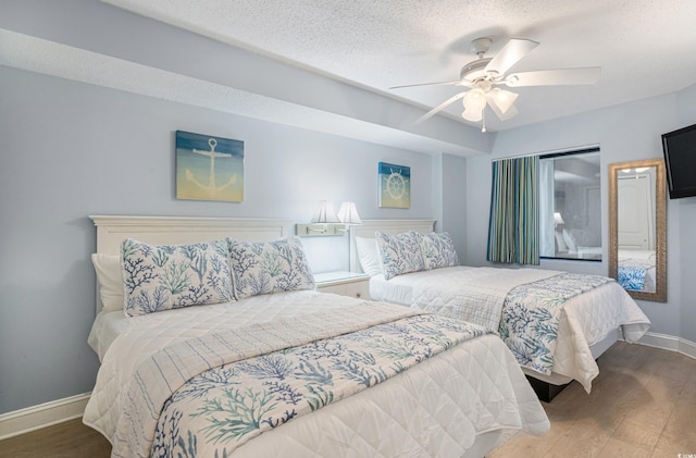 bedroom featuring a textured ceiling, ceiling fan, wood finished floors, and baseboards