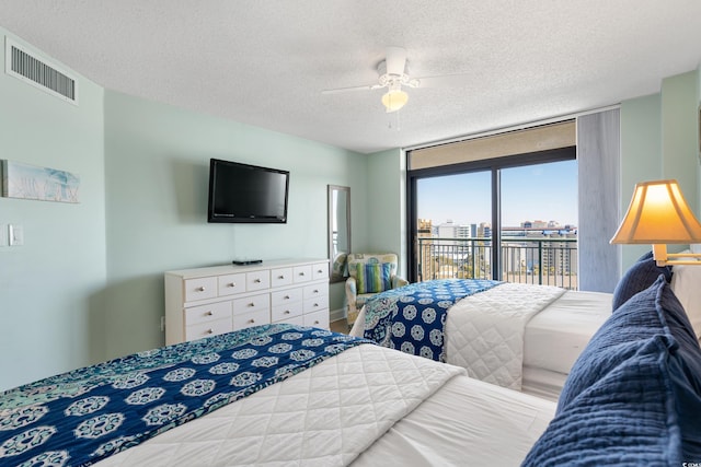 bedroom with a textured ceiling, ceiling fan, visible vents, access to outside, and floor to ceiling windows