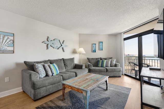 living area with a textured ceiling, floor to ceiling windows, wood finished floors, and baseboards