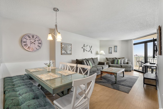 dining space with a textured ceiling, a chandelier, and wood finished floors