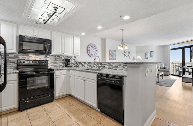 kitchen featuring white cabinetry, a sink, a peninsula, and black appliances