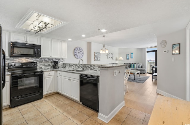 kitchen with black appliances, a peninsula, a sink, and white cabinets