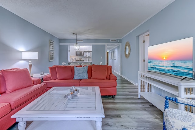 living area featuring ornamental molding, visible vents, baseboards, and wood finished floors