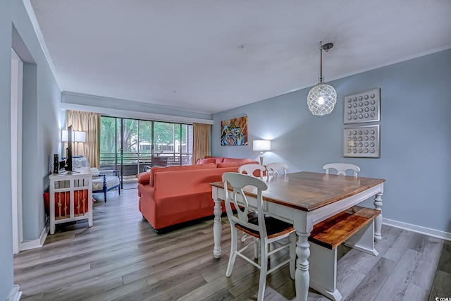 dining space with baseboards, ornamental molding, and wood finished floors