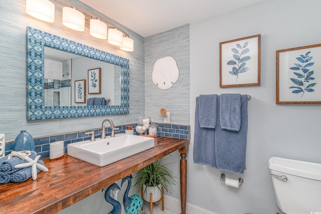 half bath with toilet, decorative backsplash, and a sink