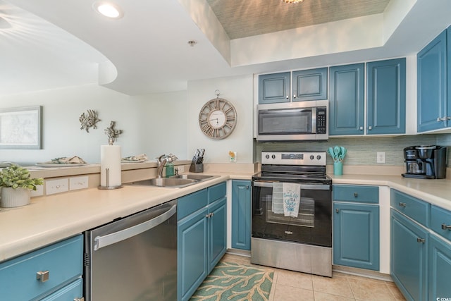 kitchen featuring light tile patterned floors, stainless steel appliances, light countertops, blue cabinetry, and a sink