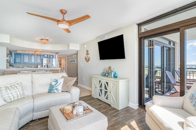 living area featuring visible vents, dark wood-style flooring, a ceiling fan, and baseboards