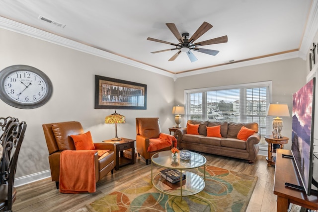 living area with ceiling fan, light wood-style flooring, visible vents, baseboards, and crown molding