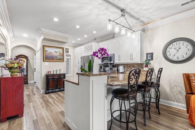 kitchen featuring a peninsula, stainless steel appliances, visible vents, white cabinetry, and decorative light fixtures