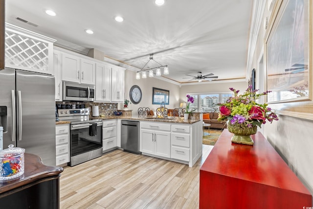 kitchen featuring pendant lighting, stainless steel appliances, open floor plan, white cabinetry, and a peninsula