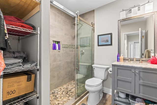 bathroom featuring a stall shower, vanity, toilet, and wood finished floors