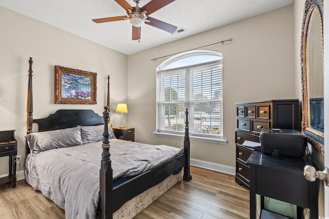 bedroom featuring a textured ceiling, light wood-type flooring, visible vents, and baseboards