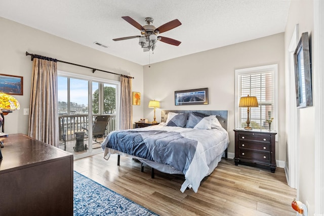 bedroom featuring access to exterior, visible vents, light wood-style floors, and a textured ceiling